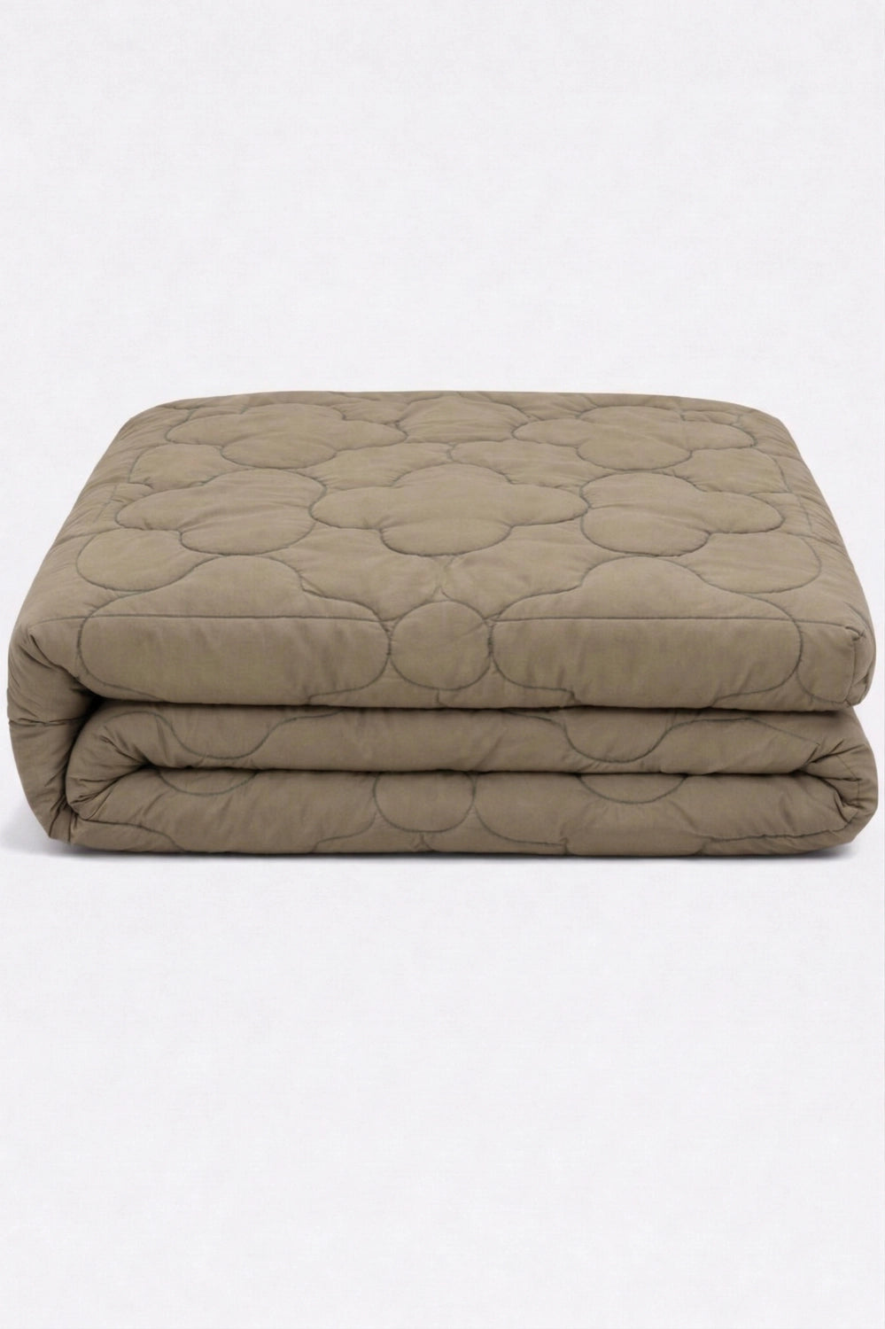 folded beige comforter with clover quilted pattern neatly stacked to highlight soft padded texture